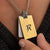 Close-up of the Bandor Military Tag pendant worn over a dark knit: 18k gold plate with the cut-out bolt seal, engraved platinum dog tag and black diamond bail. Luxury men's tag necklace.