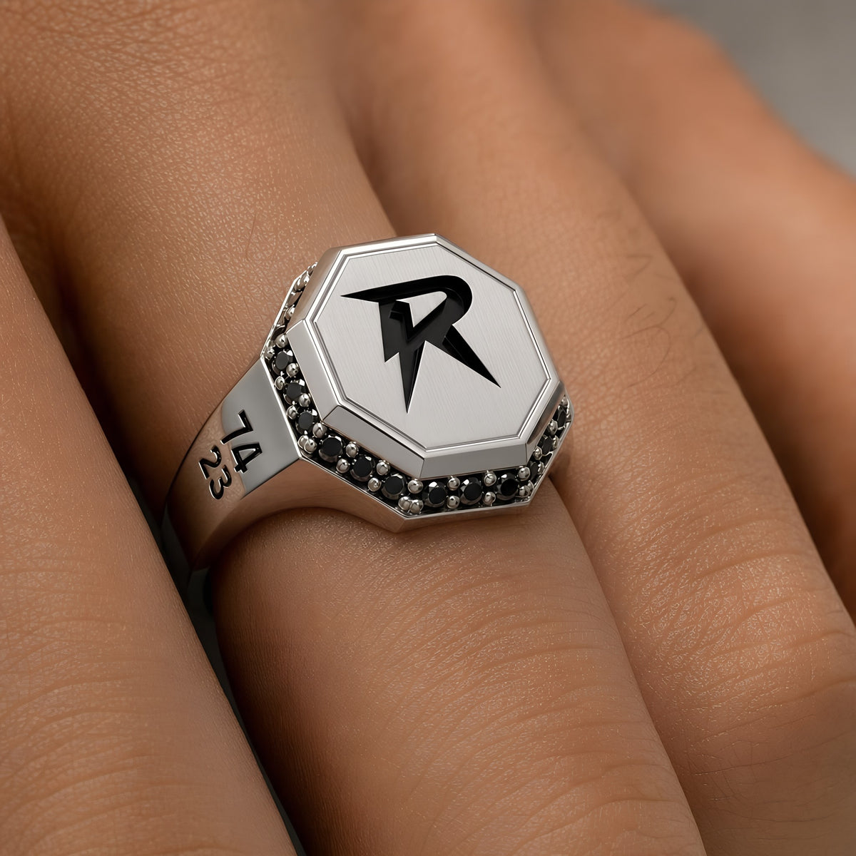 Close-up of the Bandor Signet Ring on the finger: octagonal solid platinum face, bolt seal, natural black diamond halo and 7423 engraving. Luxury men's platinum signet ring.