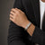 Man in a charcoal blazer wearing the Bandor Vanguard Cuff in platinum on his wrist, black diamond plaque visible
