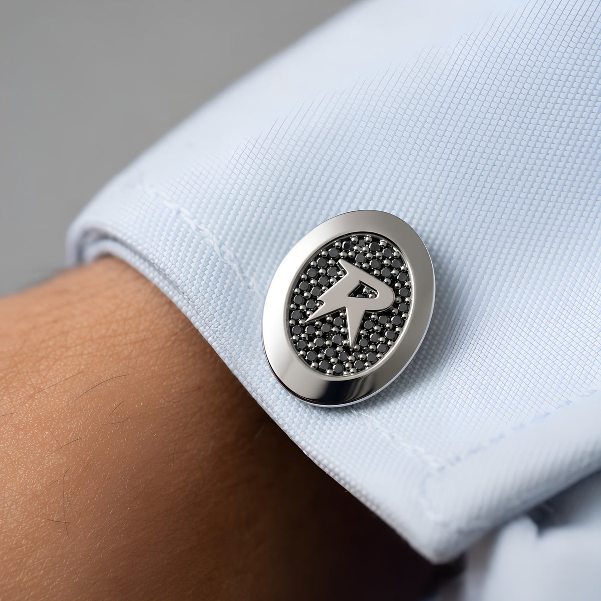 Close-up of a Bandor Vault Cufflink on a french shirt cuff: natural black diamond pave around the raised solid platinum bolt seal. Luxury men's platinum and black diamond cufflinks.